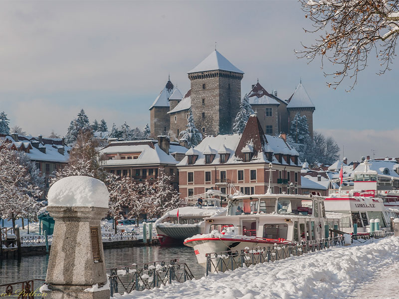 Snow covered houses and boats along the Annecy lake